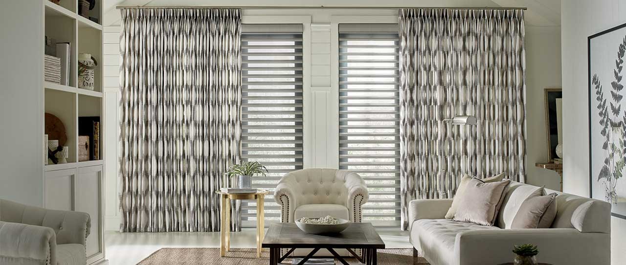 Living room with white sofa and round chandler.  Curtains with a pattern hang in the background